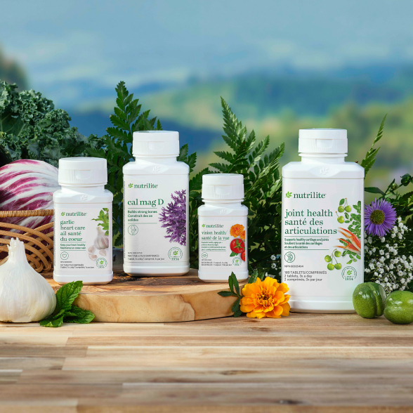 Products in the Healthy Aging Solution, including Nutrilite Garlic Heart Care, Cal Mag D, Vision Health, and Joint Health on a table surrounded by fresh vegetables and florals.