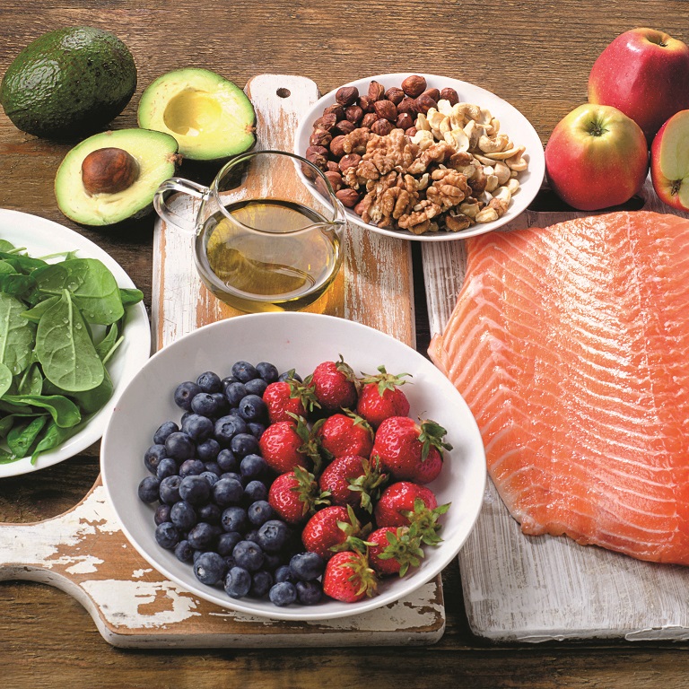 An array of mood-boosting foods in bowls and on cutting boards, including salmon, berries, spinach and whole grains.