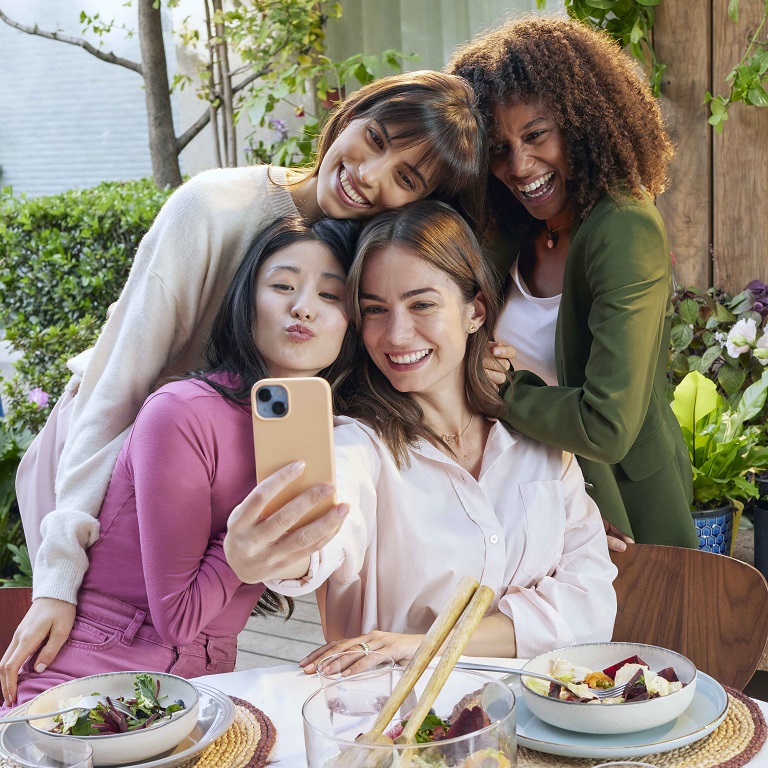 A diverse group of smiling women poses for a selfie.